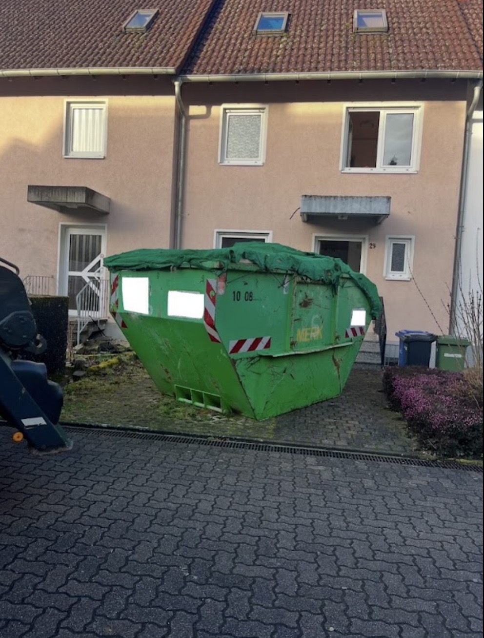 Abgedeckter Container vor einem Wohngebäude