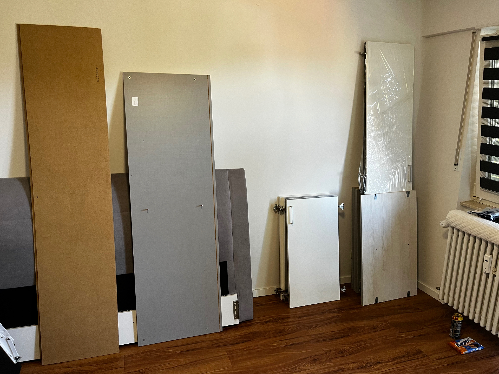 Demontierte Möbelplatten und Bettteile im leeren Zimmer