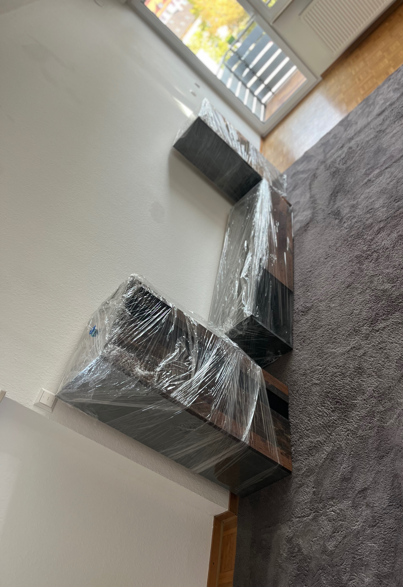 In Stretchfolie verpackte Schrankelemente stehen transportbereit im Zimmer